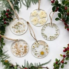 four glass ornaments with dried flowers and greenery