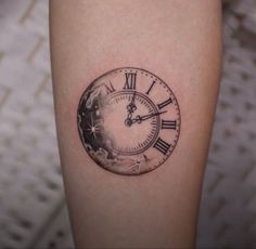 a small clock tattoo on the arm