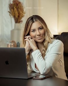 a woman sitting at a table with her laptop computer in front of her, smiling