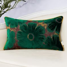 a green pillow sitting on top of a white couch next to a potted plant