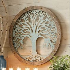 a wooden wall hanging with a tree cut out in the center and candles around it