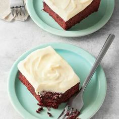 two pieces of red velvet cake with white frosting on plates next to each other