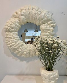 there is a vase with flowers in it and a mirror on the wall behind it