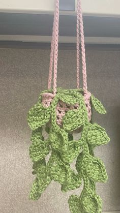 a crocheted green plant hanging from a hook on a wall in a room