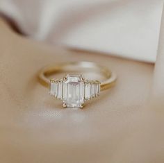 an engagement ring with three baguettes on it sitting on top of a white cloth