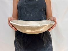 a person in overalls holding a bowl with one hand on the other and wearing an apron