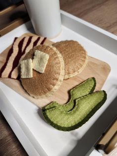 some food is sitting on a cutting board next to a glass of milk and an avocado