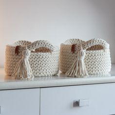 two crocheted baskets sitting on top of a white shelf next to each other