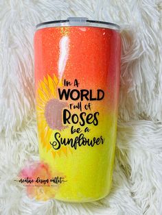 a yellow and red tumbler with the words in a world full of roses be a sunflower on it