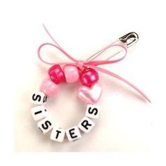 a pink and white bracelet with the word sister on it, hanging from a hook