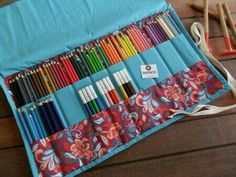 an assortment of colored pencils and crayons in a blue case on a wooden table