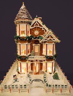 a lighted gingerbread house with snow on the ground