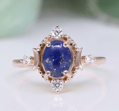 a ring with a blue stone surrounded by three diamonds on top of it, sitting on a white surface