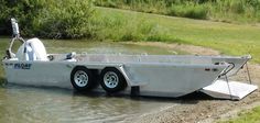 a boat sitting on the side of a river next to a grass field and trees