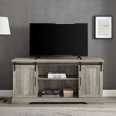 a flat screen tv sitting on top of a wooden entertainment center next to a lamp