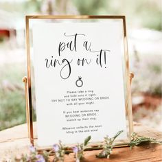 a ring game sign sitting on top of a piece of wood next to purple flowers