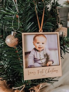 a baby's first christmas ornament hanging from a tree