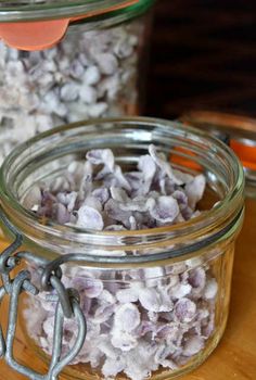 two jars filled with sea shells on top of a wooden table