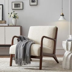 a living room with white furniture and pictures hanging on the wall, including a chair