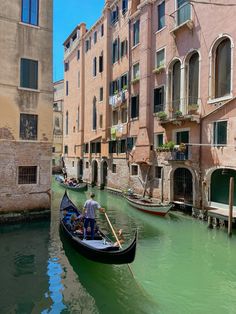 a gondola in the middle of a canal with buildings on both sides and one man sitting inside