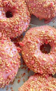 pink donuts with sprinkles on them sitting in a pile together,