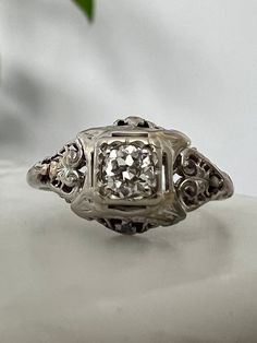 Offered here is an amazing vintage/antique diamond and filigree 18k white gold ring.  The setting has amazing filigree details on the shoulders with one old European cut diamond with plenty of fire and sparkle. The diamond is estimated VS clarity and H color and measures about 4.4 mm and estimated at .35 Ct, setting limits exact grading.  Ring is a size 9 and it weighs 2.6 grams, stamped and tests as 18k white gold. Please note this ring is in antique/vintage condition and has minor wear and imp Antique White Diamond Filigree Ring, Antique Diamond Filigree Ring, Antique Silver Diamond Filigree Ring, Antique Silver Filigree Diamond Ring, Antique Diamond Filigree Ring Collectible, Vs Diamond, European Cut Diamonds, Antique Diamond, White Gold Ring