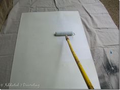 a white piece of paper with a paint roller on it and a yellow stick sticking out of it