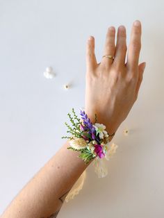 a woman's hand with a flower wrist corsage on top of it