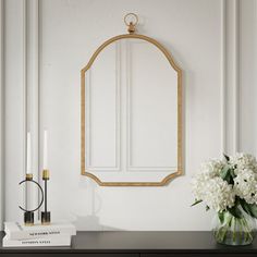 a vase with white flowers on top of a table next to a mirror and candles