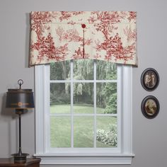 an open window with a red and white curtain in front of two pictures on the wall