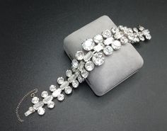 a diamond bracelet is displayed on a gray cloth case, with a chain attached to it