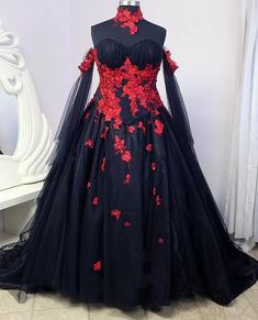 a black dress with red flowers is on display in front of a mannequin