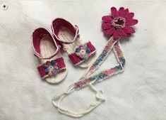 three crocheted baby shoes and a flower