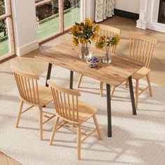 a dining room table with four chairs and a vase full of flowers on the table