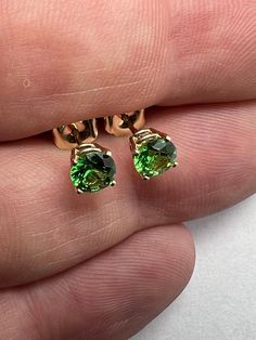 1 carat Tsavorite garnet stud earrings set in 14k yellow gold.  5mm prong set 14k yellow gold green grossular garnet earrings. 1.05 carat, round brilliant cut, 5mm tsavorite grossular green garnets from Kenya. All natural untreated, precision cut, in house, for great brilliance and color. prong set in solid 14k yellow gold. Picture of 5mm prong set next to 4mm bezel set for reference only. 1mm in gemstone size makes a large difference in appearance! See more of our earrings here .  https://www.e Yellow Gold Tsavorite Earrings As Gift, Tsavorite Yellow Gold Earrings For Gift, 14k Gold Jewelry Set With Green Matching Earrings, Yellow Gold Tsavorite Gemstone Earrings, Yellow Gold Tsavorite Earrings Fine Jewelry, Tsavorite Earrings For Anniversary In Fine Jewelry Style, Green Solitaire Round Cut Jewelry, Fine Jewelry With Prong Setting For May Birthstone, Fine Jewelry Earrings For May Birthstone