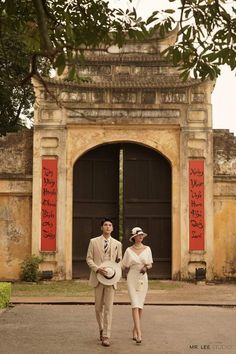 a man and woman walking in front of an old building