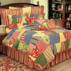 a bed covered in colorful quilts and pillows