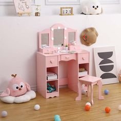 a pink vanity with mirror and stool in a child's room