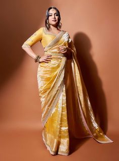 Editor's Note Elevate your style with our Haldi Yellow Sunaina Wrinkled Tissue Saree, a stunning blend of grace and royalty. Crafted from wrinkled yellow tissue with golden borders adorned with Resham and Zardozi handwork, it exudes elegance. The minimalist opulence of our Signature Matsya Delicacy shines through in this ensemble. The blouse features a sweetheart neckline, showcasing its regal allure, and is crafted from silk Chanderi with elbow sleeves, border details, sequin sprinklers, and mo Tissue Saree Blouse Designs Latest, Yellow Saree For Haldi, Saree For Haldi, Yellow Banarasi Saree, Yellow Sharara, Bridesmaid Outfits, Saree Accessories, Saree Drape, Fashionable Saree