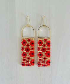 two pairs of red and black beaded earrings on a white surface with gold hooks