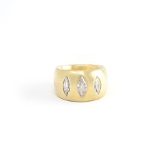 a yellow gold ring with three pear shaped diamonds on the side, set against a white background