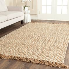 a living room area with a white couch and large rugs on the wooden floor