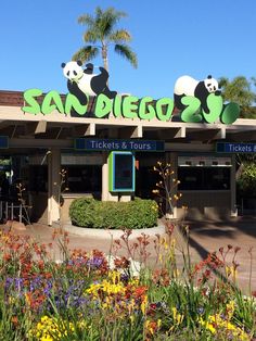 the entrance to san diego zoo with pandas on it's sign and flowers