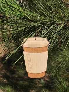 a wooden coffee cup ornament hanging from a pine tree