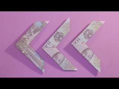 three origami arrows on a pink background with one arrow cut in half and the other made out of money