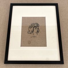 a drawing of a woman's face is framed in a black and white frame