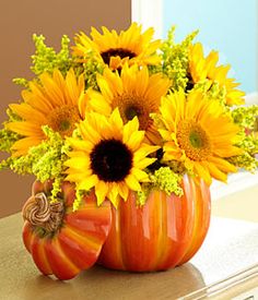 a pumpkin shaped vase filled with sunflowers