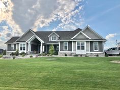 a large house sitting in the middle of a green field with a truck parked nearby