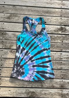 Days at the beach will be even better with a one of a kind Tie Dye Tank Top! This pastel racer back tie dye tank top is perfect for days at the pool, music festivals, a beach vacation or dressed up for a night out! Perfect for a gift or a treat for yourself. I discovered tie dye during the pandemic and it quickly became my new hobby and passion. I am loving experimenting with colors and techniques to create colorful, funky shirts. The shirts are Ideal T by Next Level, a 60%cotton/40% polyester blend. The shirts come in women's sizes S, M, L, XL & XXL.  Please note the shirt is a fashion fit and tends to fit tighter than a normal traditional fit, consider ordering one size larger than normal for a traditional fit. Patterns will vary slightly by size.  The shirts have been washed and are rea Casual Multicolor Tank Top For Yoga, Casual Blue Tank Top For Festivals, Blue Casual Tank Top For Festival, Fitted Acid Wash Casual Tank Top, Blue Tank Top For Beach Season, Multicolor Stretch Racerback Tank Top, Multicolor Summer Workout Tank Top, Fitted Cotton Tie Dye Tank Top, Fitted Tie Dye Cotton Tank Top