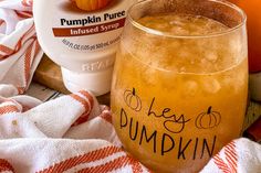 an orange drink sitting on top of a table next to a bottle of pumpkin puree